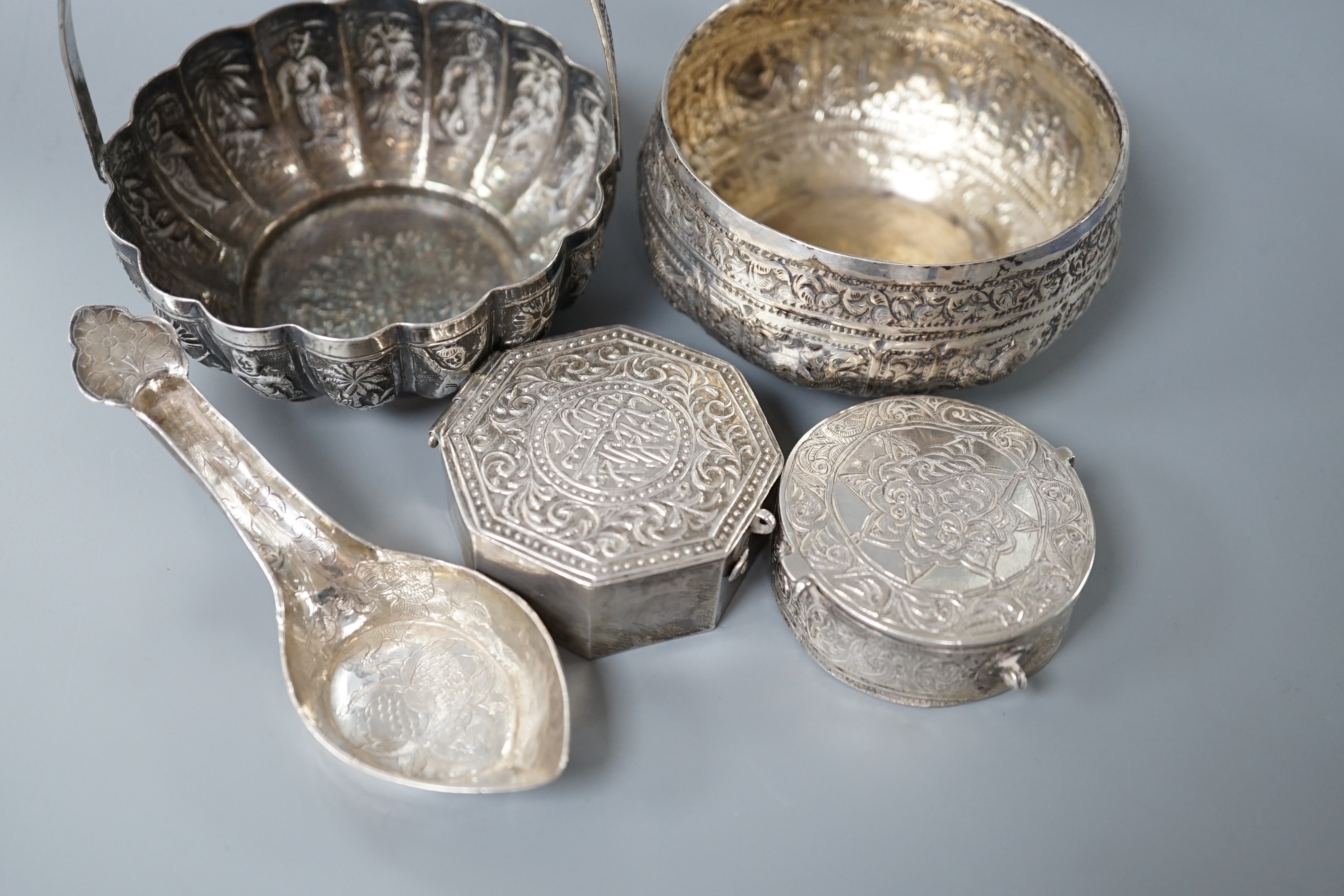 A Burmese? white metal bonbon basket, height 10.1cm and a similar bowl, two Persian white metal boxes and a spoon.